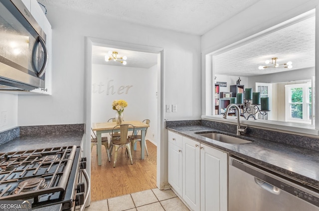 kitchen featuring a textured ceiling, an inviting chandelier, a sink, and stainless steel appliances