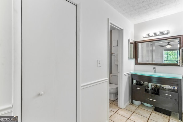 bathroom with toilet, a textured ceiling, tile patterned flooring, and vanity
