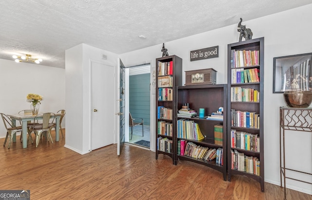 living area featuring baseboards, wood finished floors, and a textured ceiling