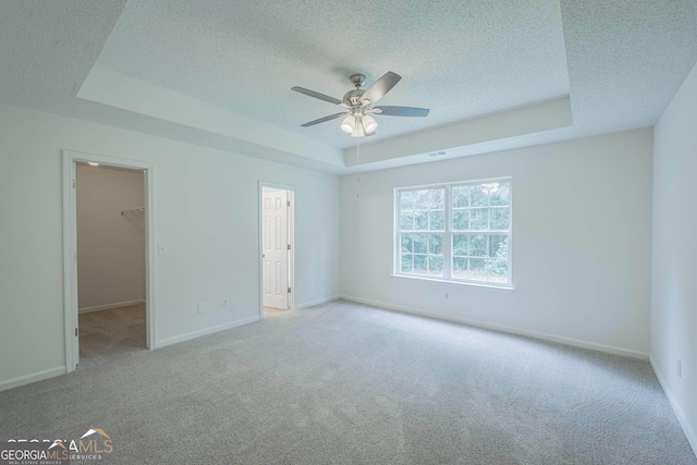 460 Mckneely Rd, Griffin, GA 30224 - unfurnished bedroom with a tray ceiling, a textured ceiling, carpet flooring, a walk in closet, and baseboards
