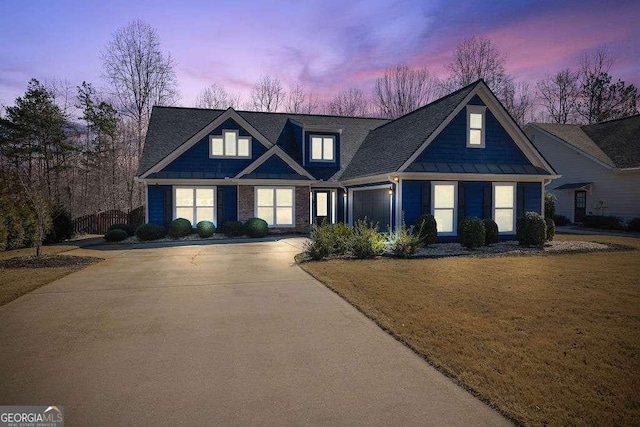 craftsman-style home featuring driveway, a garage, a standing seam roof, and a front yard