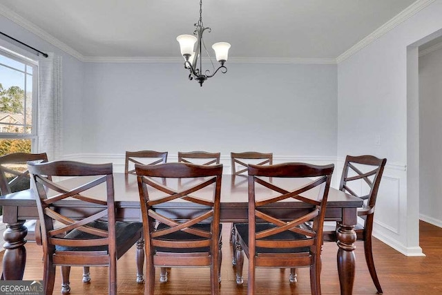 dining space featuring ornamental molding, wainscoting, an inviting chandelier, and wood finished floors