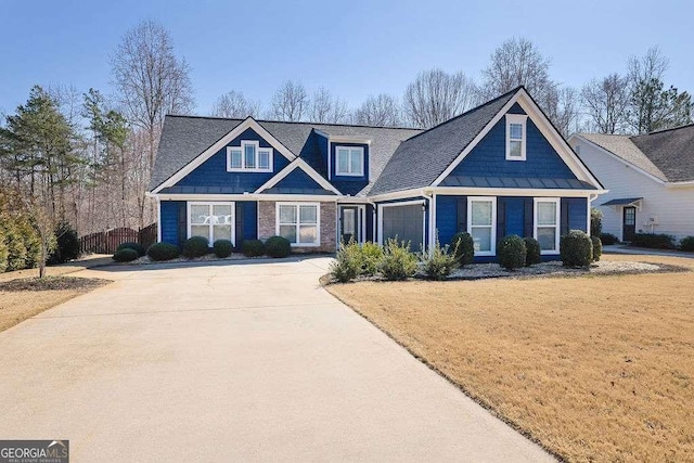 craftsman-style house with a front yard, a standing seam roof, a garage, and driveway