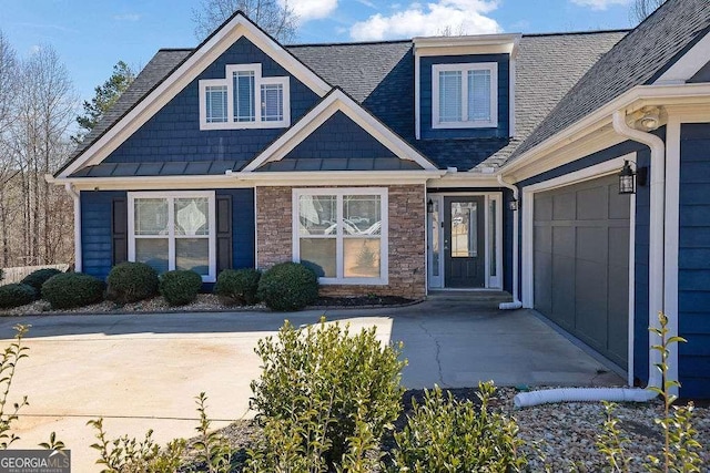 exterior space with roof with shingles, a standing seam roof, a garage, and stone siding