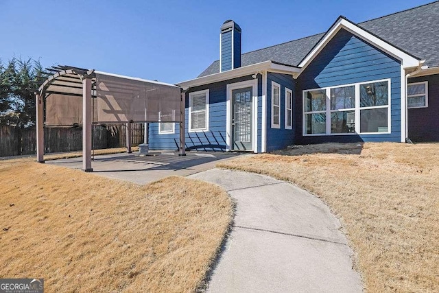 back of house featuring a patio area, a chimney, a yard, and a pergola