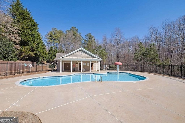 community pool with a storage structure, an outbuilding, a patio area, and fence