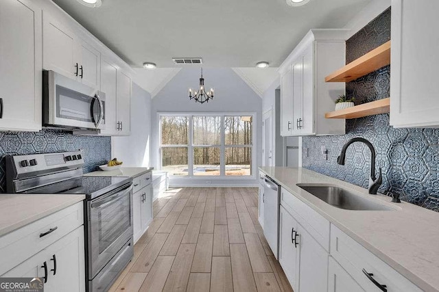kitchen featuring light wood-type flooring, open shelves, visible vents, appliances with stainless steel finishes, and a sink