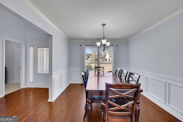 dining room featuring a chandelier, dark wood-type flooring, ornamental molding, and wainscoting