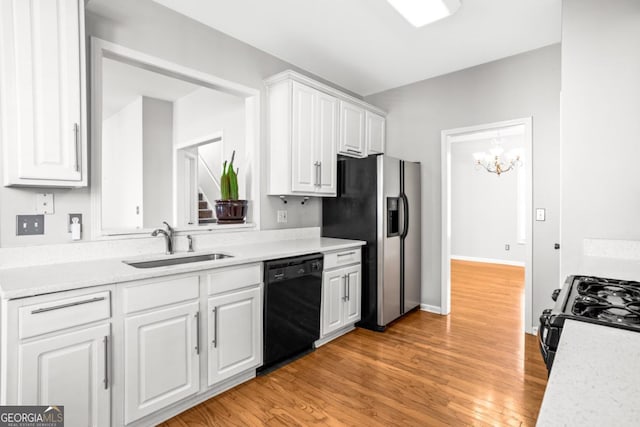 kitchen featuring white cabinets, black appliances, a sink, light countertops, and a notable chandelier