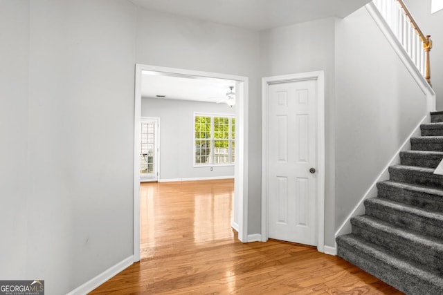 stairs featuring baseboards, a ceiling fan, and wood finished floors
