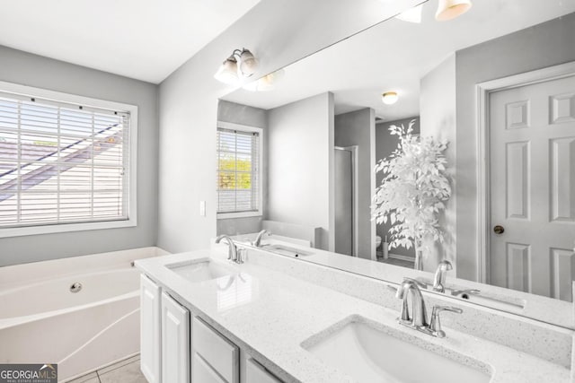 full bath featuring a garden tub, double vanity, and a sink