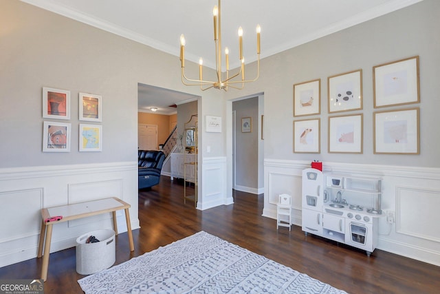 playroom with wainscoting, a notable chandelier, ornamental molding, and wood finished floors