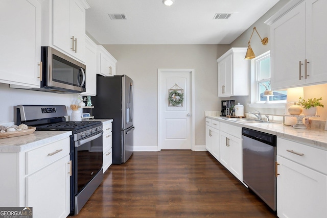 kitchen featuring dark wood-style flooring, white cabinetry, visible vents, stainless steel appliances, and a sink