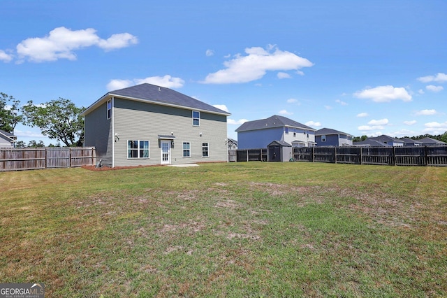 rear view of property featuring a yard, a fenced backyard, and an outbuilding