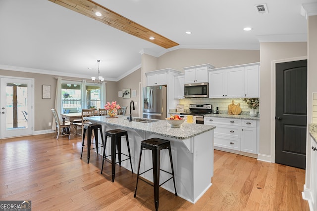 75 Flagstone Dr, Newnan, GA 30263 - kitchen featuring stainless steel appliances, a kitchen bar, vaulted ceiling, white cabinets, and an island with sink