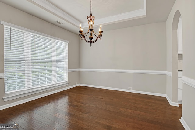 empty room featuring hardwood / wood-style floors, a raised ceiling, visible vents, arched walkways, and a chandelier