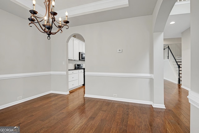 unfurnished dining area with baseboards, arched walkways, stairway, and dark wood-style flooring