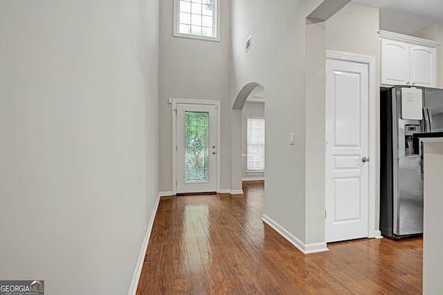 entrance foyer featuring arched walkways, hardwood / wood-style floors, a healthy amount of sunlight, and visible vents