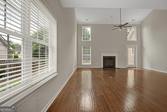 unfurnished living room featuring a fireplace with flush hearth, a ceiling fan, ornamental molding, and wood-type flooring