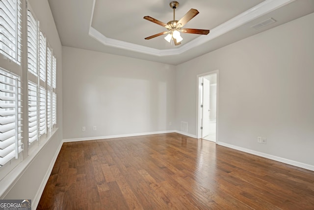 unfurnished room with wood finished floors, a ceiling fan, visible vents, and a raised ceiling