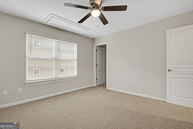 unfurnished bedroom featuring attic access, baseboards, light colored carpet, and ceiling fan