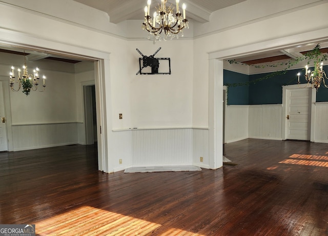 unfurnished dining area featuring wood finished floors, beam ceiling, a wainscoted wall, and an inviting chandelier