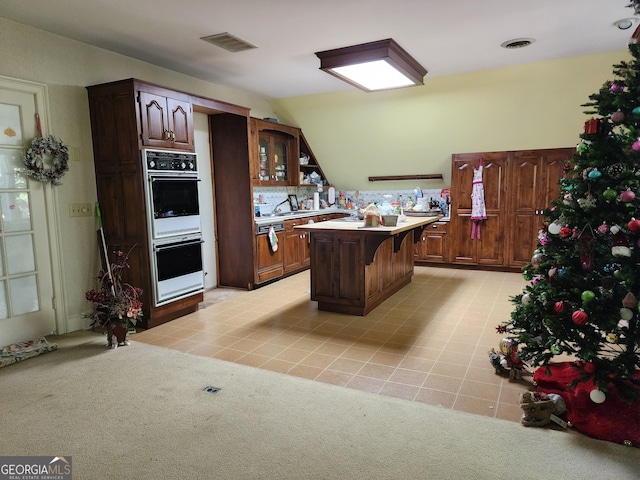 kitchen with light countertops, vaulted ceiling, visible vents, and multiple ovens