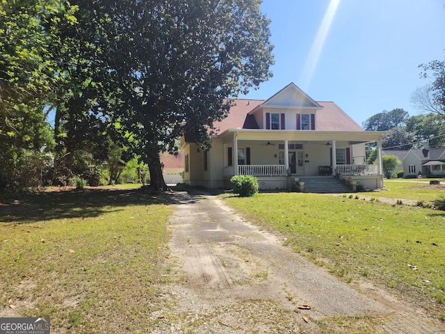 view of front facade featuring driveway, a ceiling fan, a front yard, and covered porch