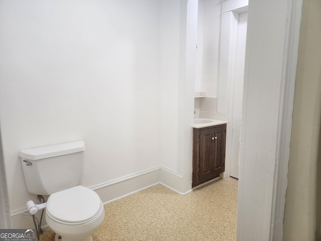 bathroom with baseboards, vanity, and toilet