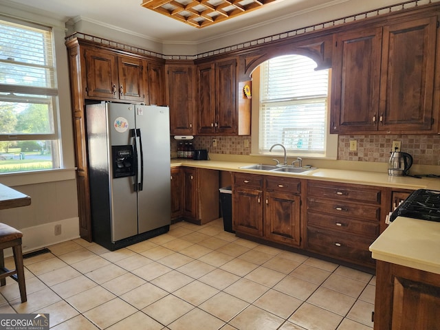 kitchen featuring crown molding, a sink, decorative backsplash, stainless steel fridge with ice dispenser, and light countertops