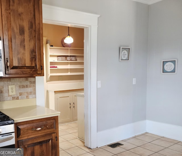 kitchen with backsplash, light countertops, gas stove, and light tile patterned floors