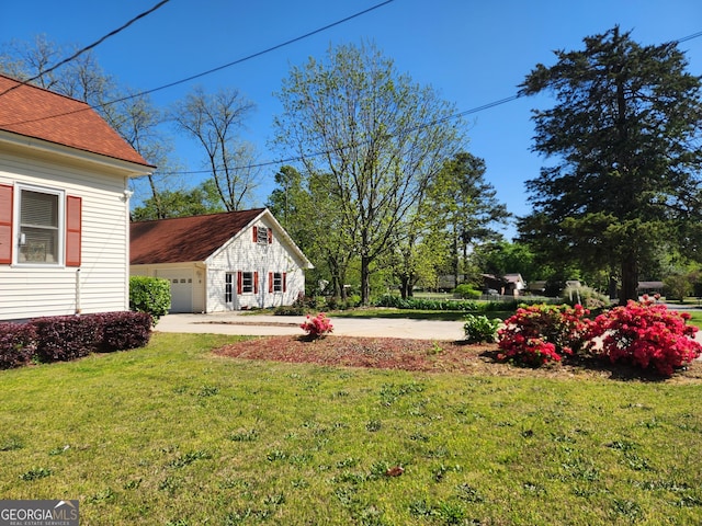 view of yard with a garage and concrete driveway