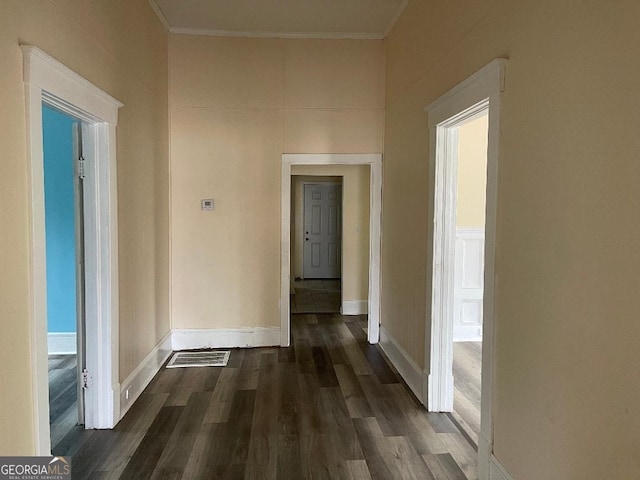 hall with crown molding, baseboards, dark wood-style floors, and visible vents