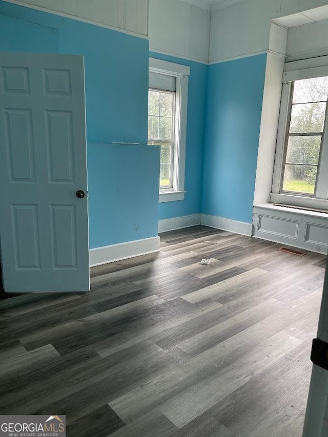 spare room featuring a wealth of natural light, baseboards, and wood finished floors