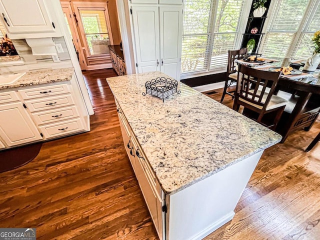 2319 Lochinver Ln SW, Conyers, GA 30094 - kitchen with dark wood-style flooring, light stone counters, white cabinetry, a kitchen island, and a sink