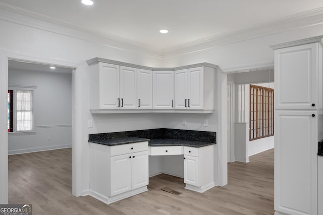 kitchen with ornamental molding, white cabinets, light wood-type flooring, and built in study area