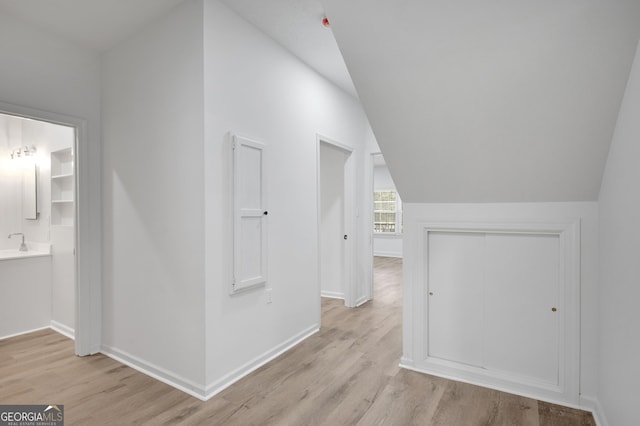 bonus room with a sink, light wood-style flooring, baseboards, and vaulted ceiling