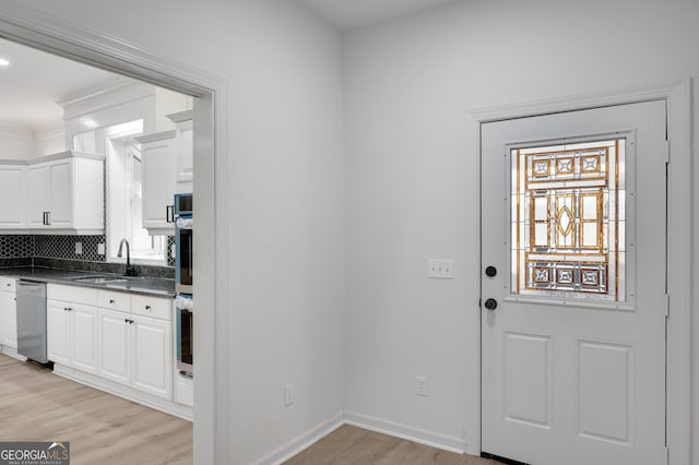 doorway to outside with a sink, baseboards, light wood-style floors, and crown molding