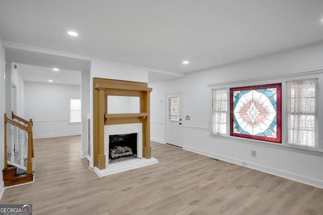 unfurnished living room with recessed lighting, stairs, light wood-style flooring, and a brick fireplace