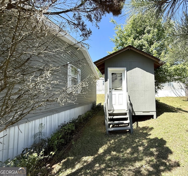 view of property exterior featuring entry steps, an outdoor structure, and a lawn