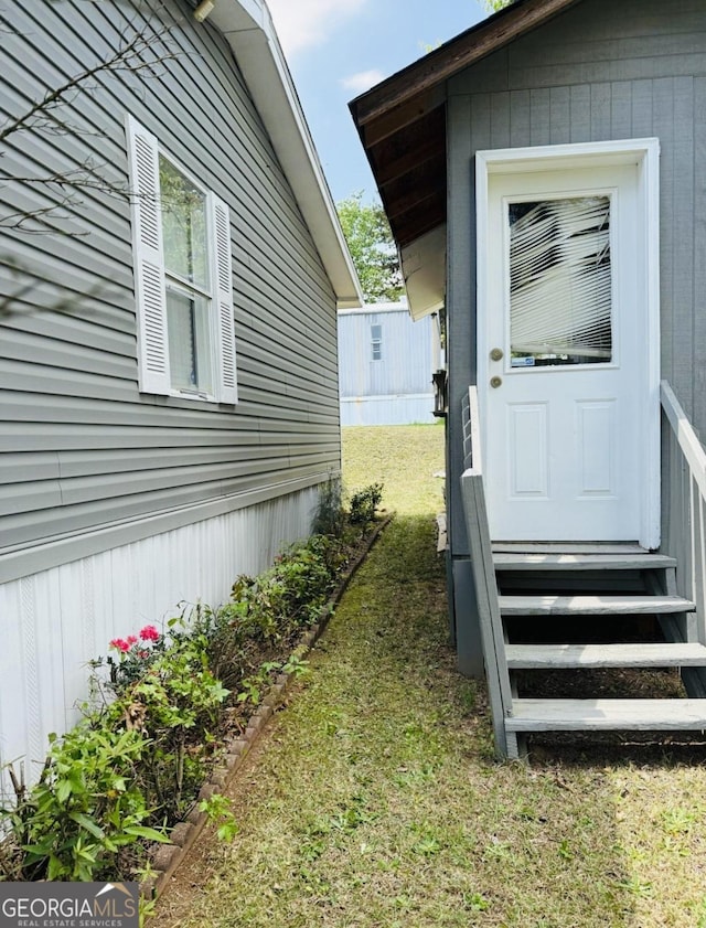view of side of property featuring entry steps and a yard