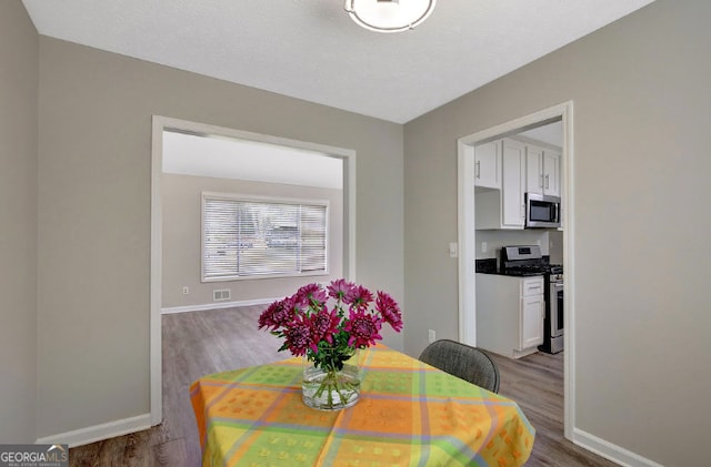 dining room featuring wood finished floors, baseboards, and visible vents