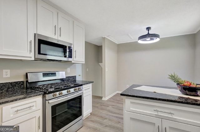 kitchen featuring white cabinetry, light wood-type flooring, appliances with stainless steel finishes, and dark stone countertops