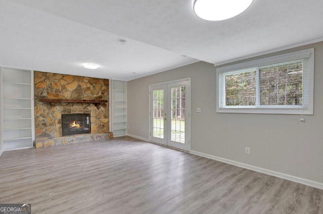 unfurnished living room with built in shelves, french doors, baseboards, and wood finished floors