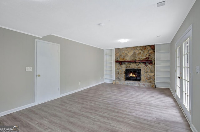 unfurnished living room featuring visible vents, baseboards, built in features, and wood finished floors