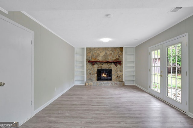 unfurnished living room with built in shelves, french doors, ornamental molding, and wood finished floors