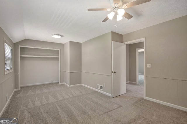 unfurnished bedroom featuring visible vents, a closet, a ceiling fan, carpet, and lofted ceiling