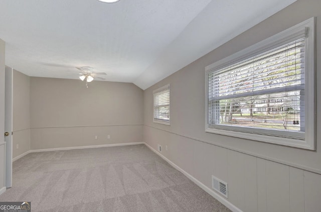 empty room featuring visible vents, baseboards, a ceiling fan, light carpet, and lofted ceiling