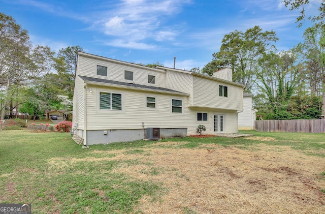 rear view of property with central AC, fence, a lawn, and a chimney