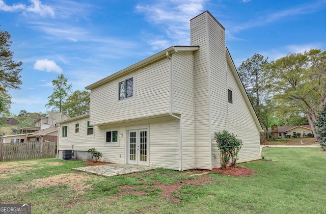 back of property with a yard, a chimney, fence, cooling unit, and french doors
